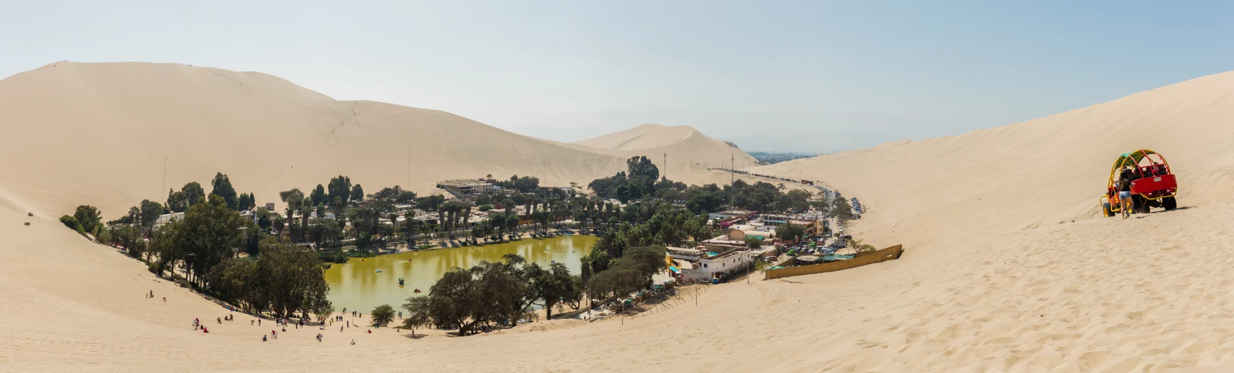 A broad view across Huacachina lagoon and its surrounding dunes