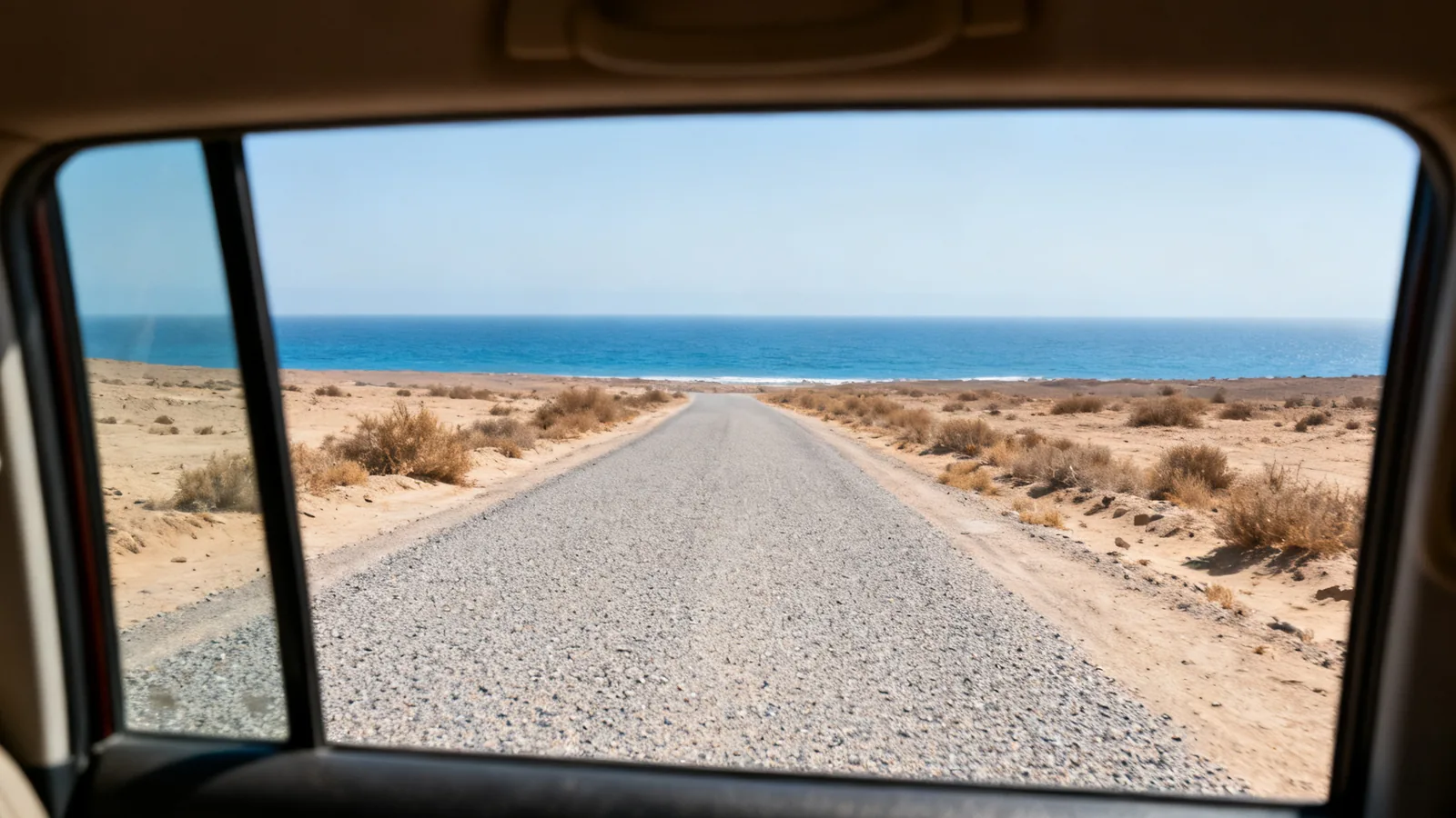 Photographic illustration of a coastal road viewed from a vehicle window