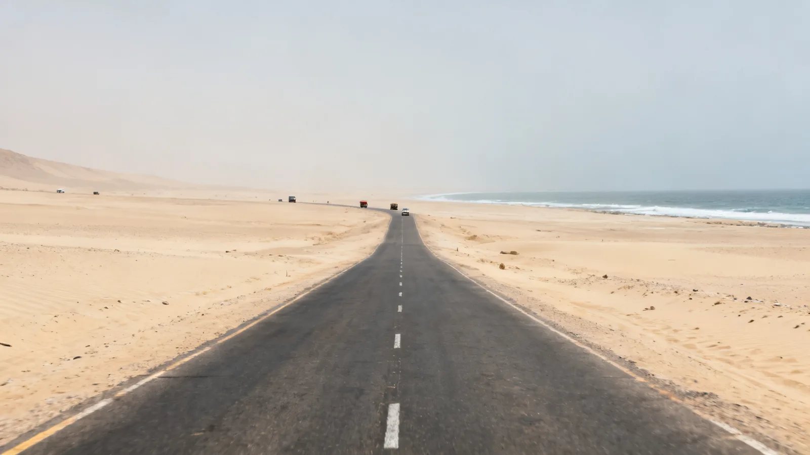 Photographic illustration of a paved road through sandy coastal desert